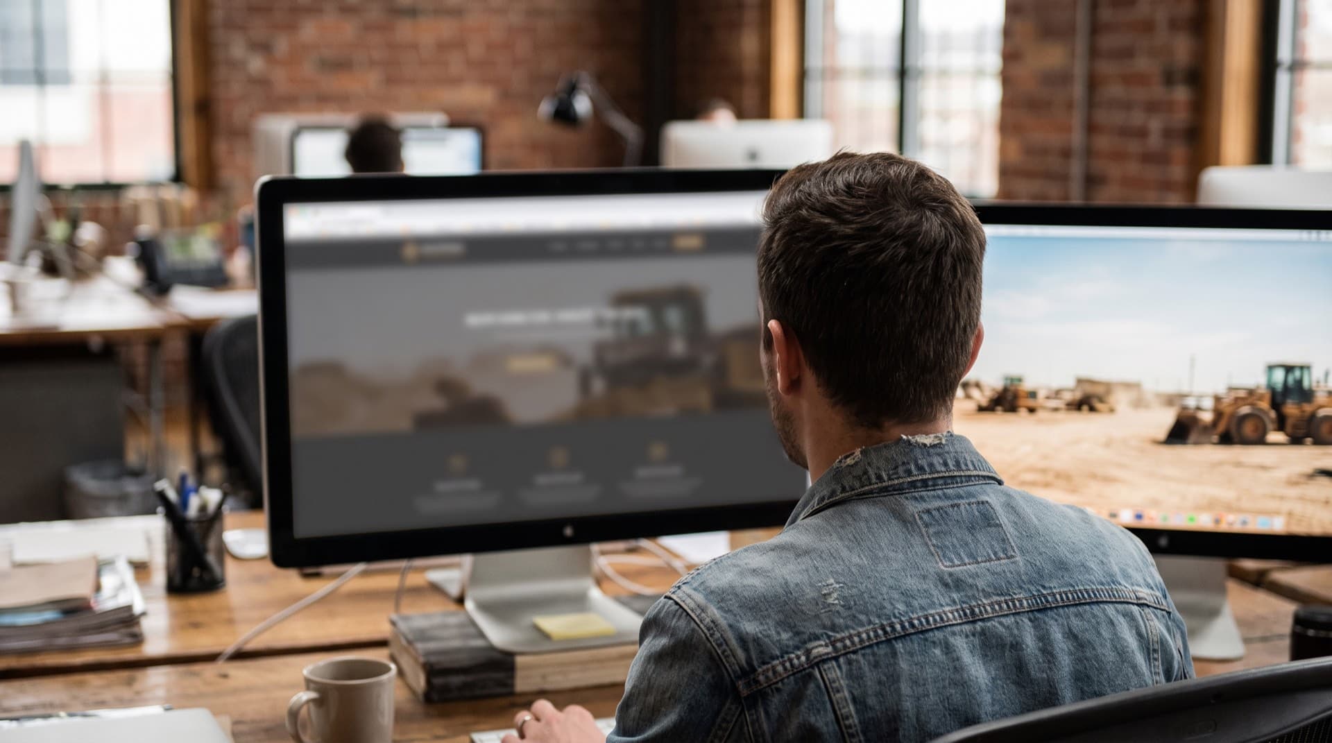 A designer building an industrial contractor website layout on a monitor